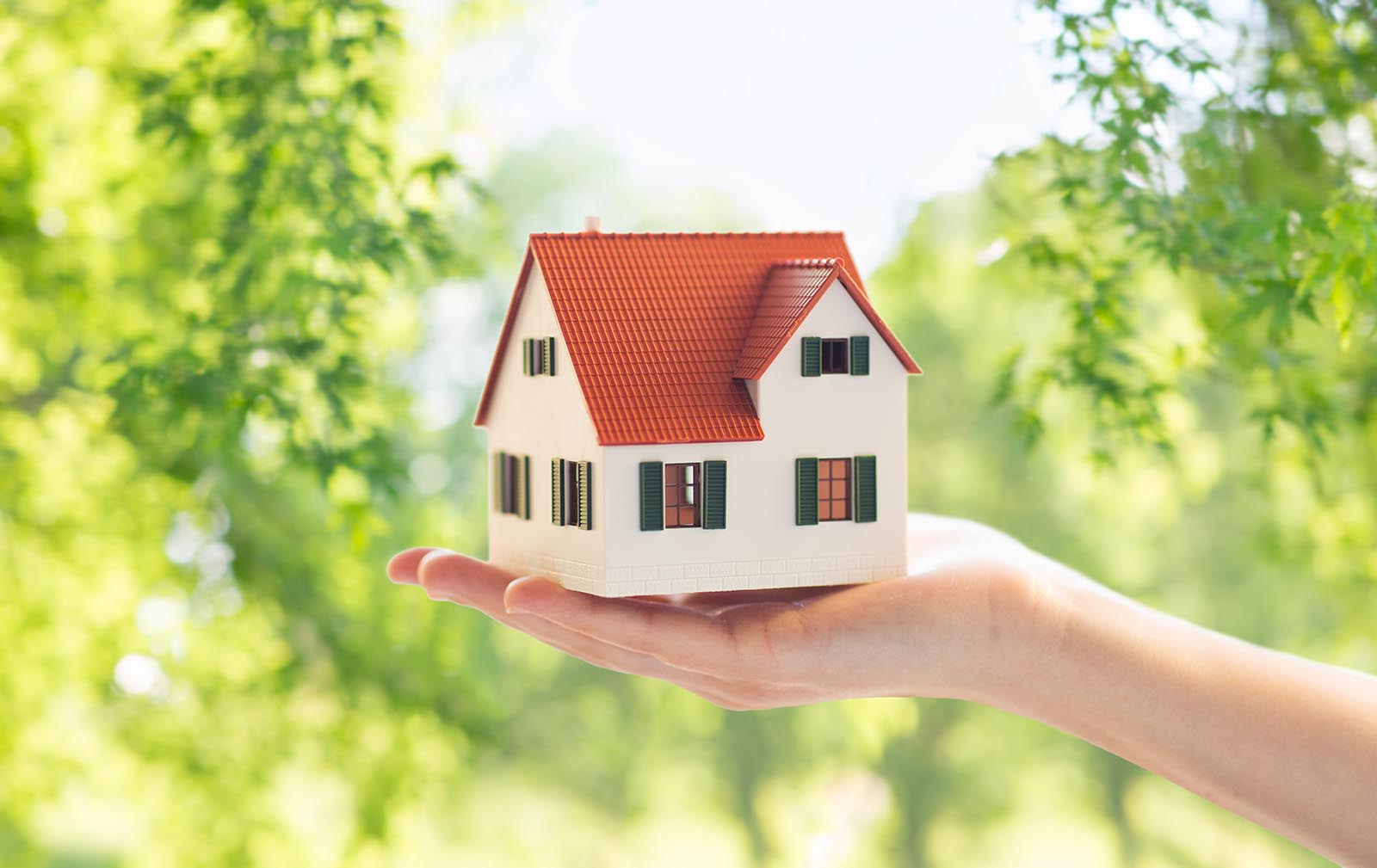 close up of hand holding house or home model