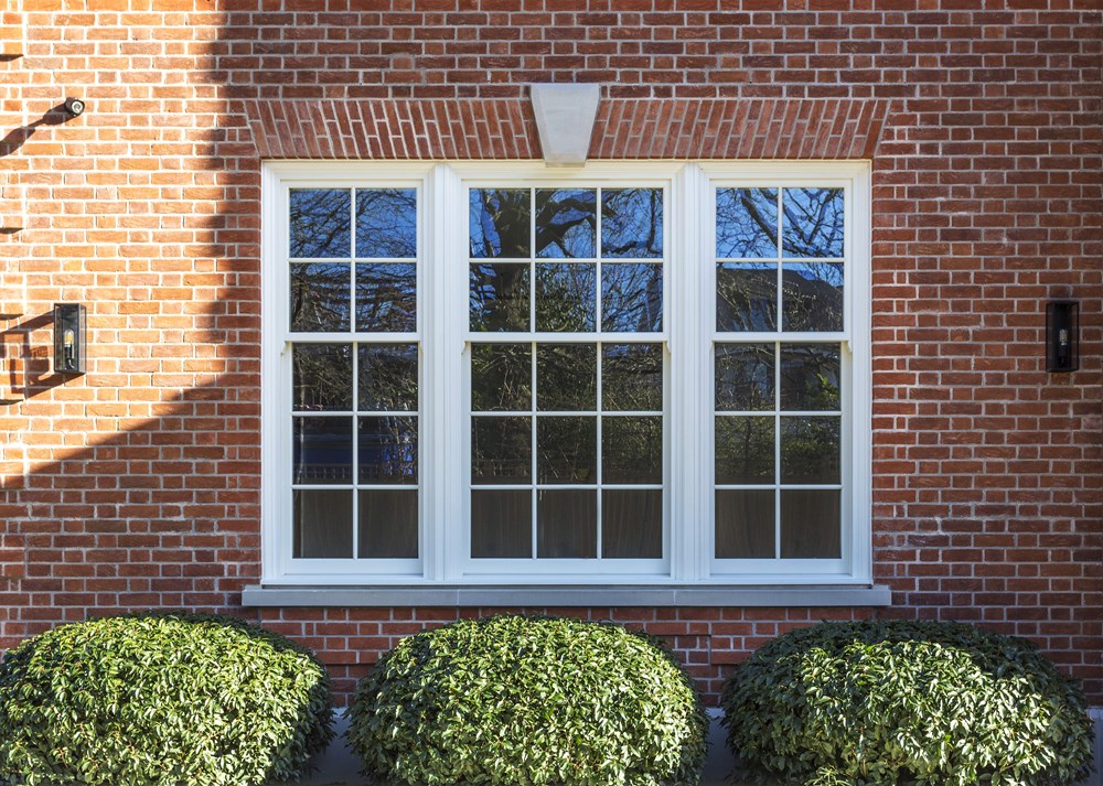 Timber box sash window painted white on a brick wall of a property