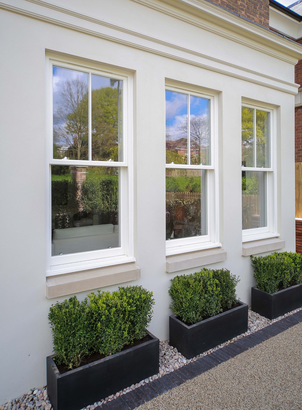 Close-up exterior shot of spring balance sash windows with green shrubbery below.